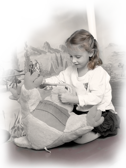 Spielendes Kind Kleines Mädchen spielt mit einem Stofftierdrachen. Sie putzt ihm mit einer riesigen Zahnbürste die Zähne.
